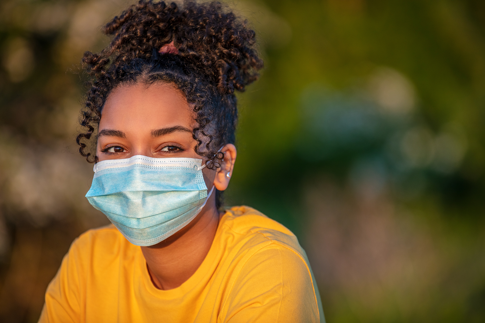 Mixed race African American teenager teen girl young woman wearing a face mask outside during the Coronavirus COVID-19 pandemic
